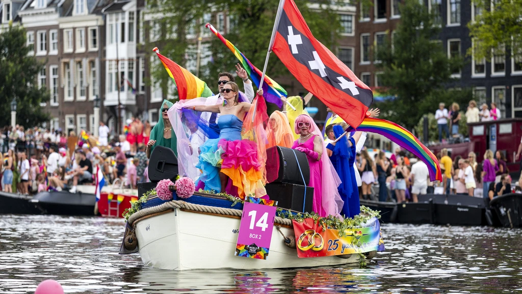 Drukte bij Amsterdamse grachten voor Canal Parade, feest in volle gang